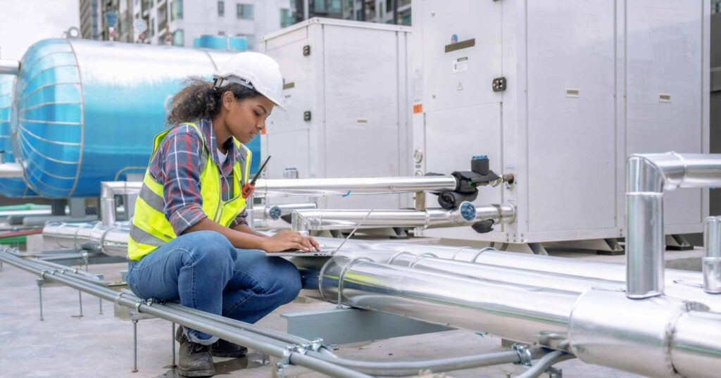 Female engineer inspects and controls the cooling system of a large factory air conditioner.