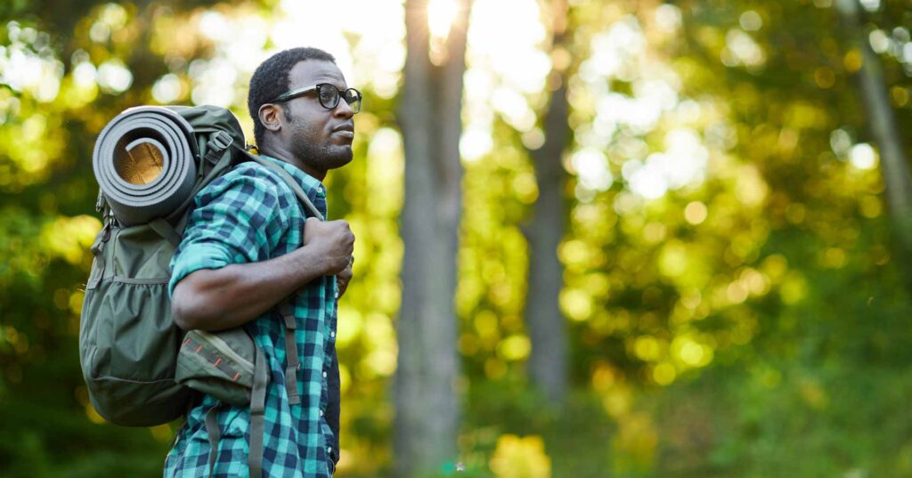 Man hiking in forest alone with backpack wearing a flannel shirt