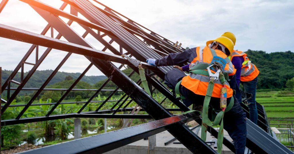 Construction worker wearing safety harness using secondary safety device connecting into 15 mm static rope using as fall restraint shingle on top of the new roof.