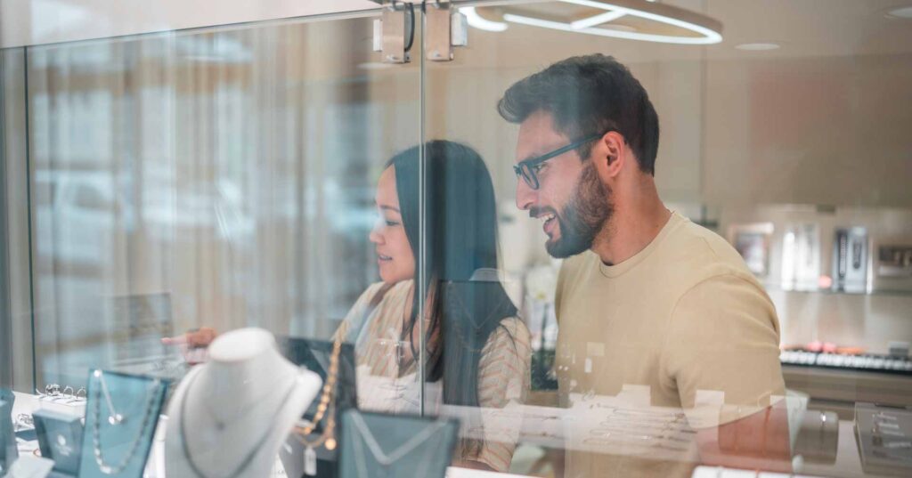 A diverse couple, consisting of an Asian female and a Hispanic male exploring the offerings in a jewelry store.