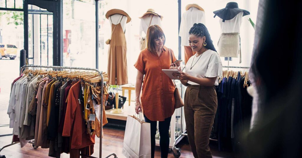 Shot of a shop assistant using a digital tablet while assisting a customer in a boutique