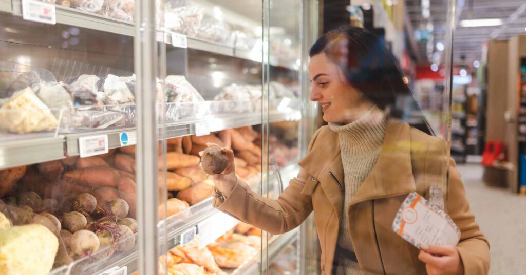 Young woman buying vegetables while grocery shopping.